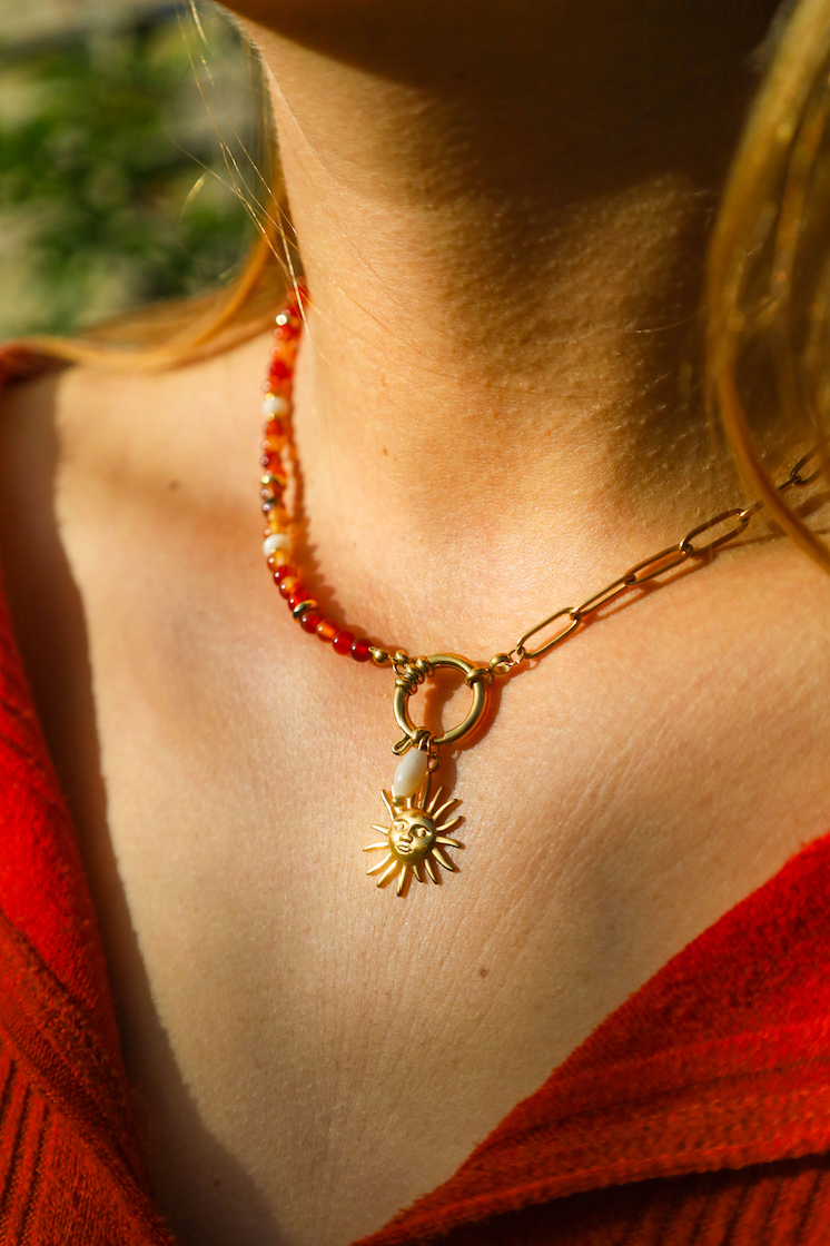 Collier asymétrique en chaine en acier inoxydable et perles de cornaline orangées avec un pendentif soleil et une perle en nacre
