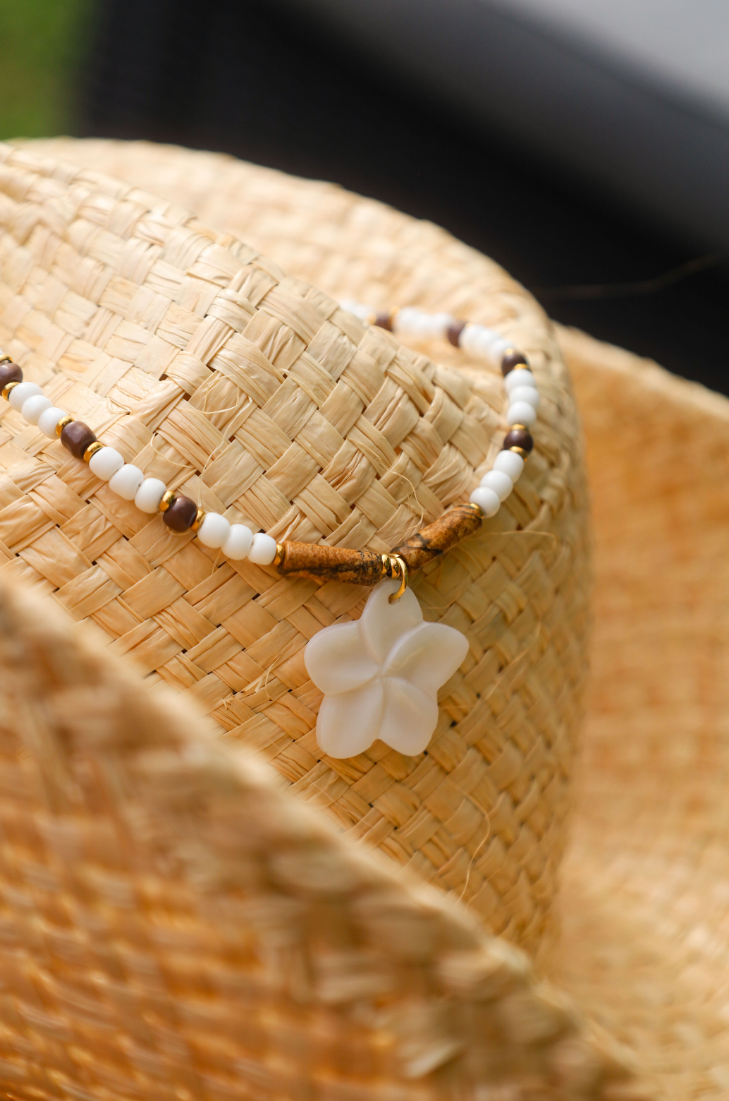 Collier en perles de rocailles blanches et une pointe de marron avec un pendentif en fleur de nacre.