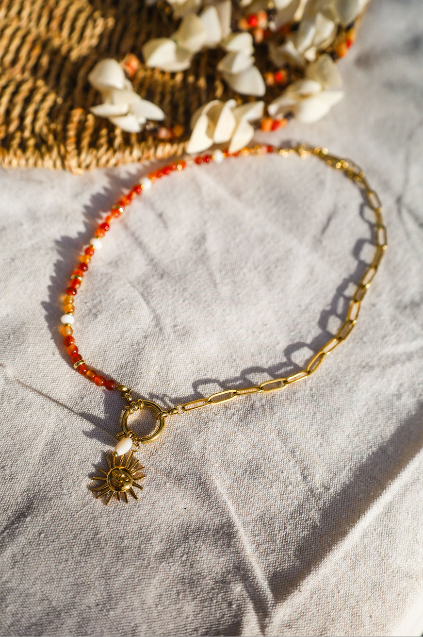 Collier asymétrique en chaine en acier inoxydable et perles de cornaline orangées avec un pendentif soleil et une perle en nacre