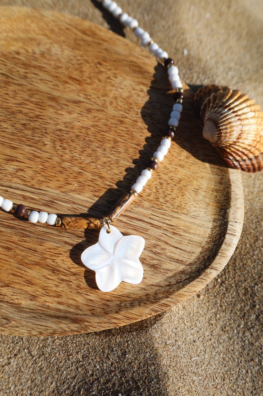 Collier en perles de rocailles blanches et une pointe de marron avec un pendentif en fleur de nacre.