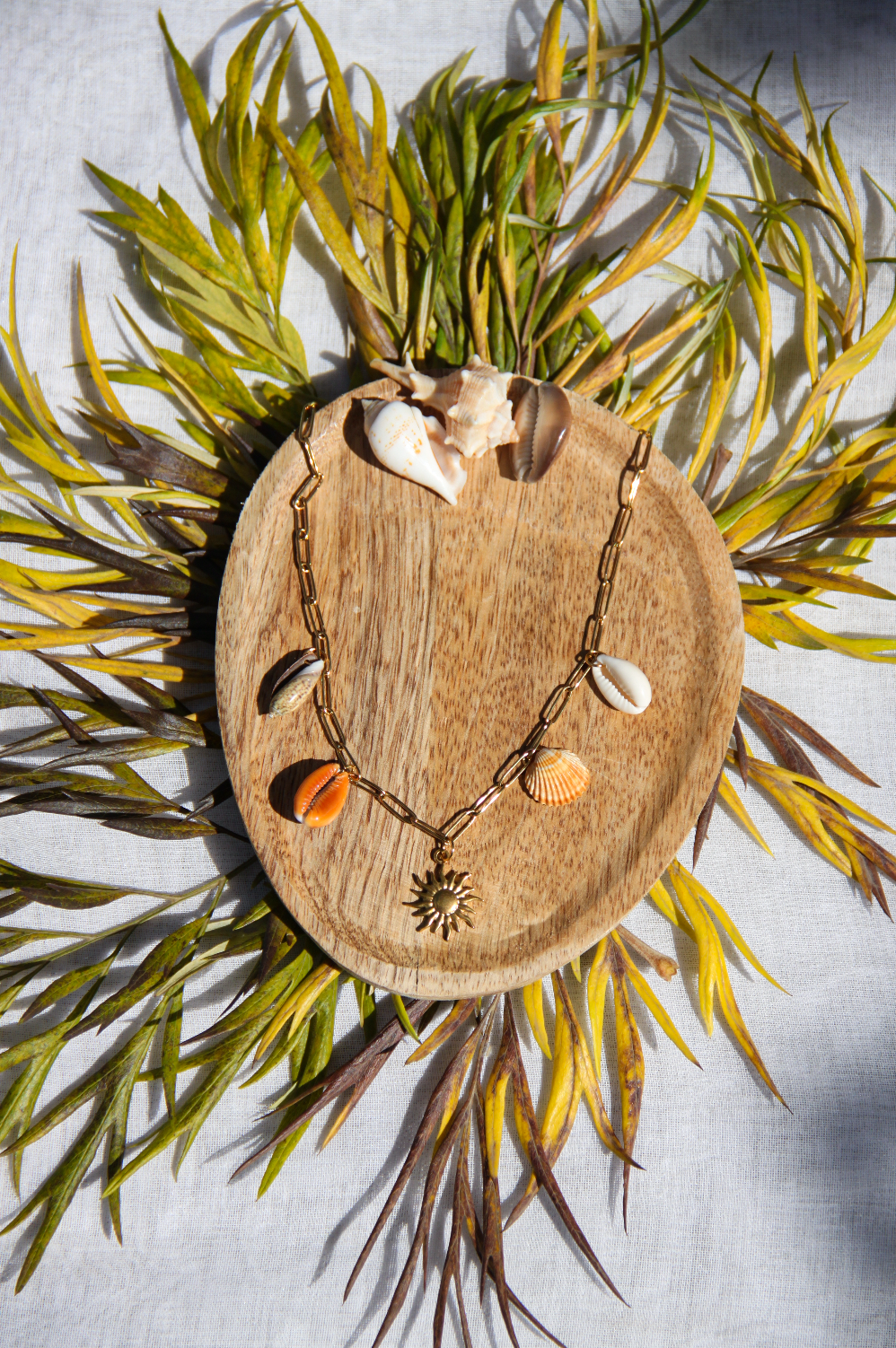 Collier avec chaine en acier inoxydable et 4 coquillages différents avec un petit pendentif soleil