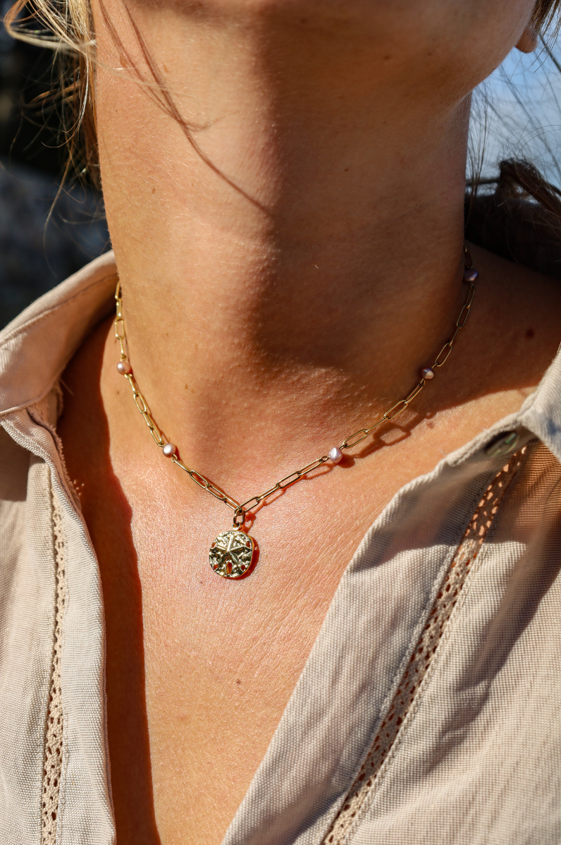 Collier en chaine dorée et perles de cultures violetes au pendentif dollar des sables
