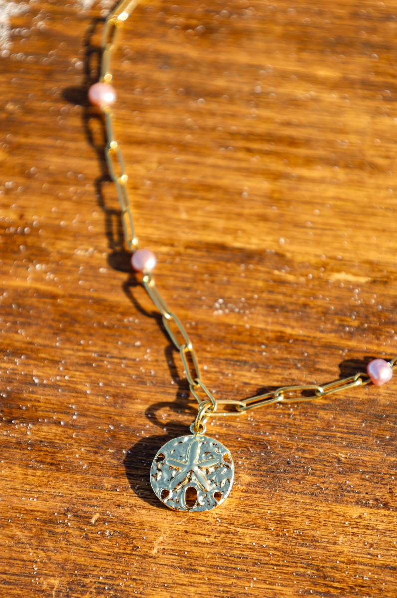 Collier en chaine dorée et perles de cultures violetes au pendentif dollar des sables