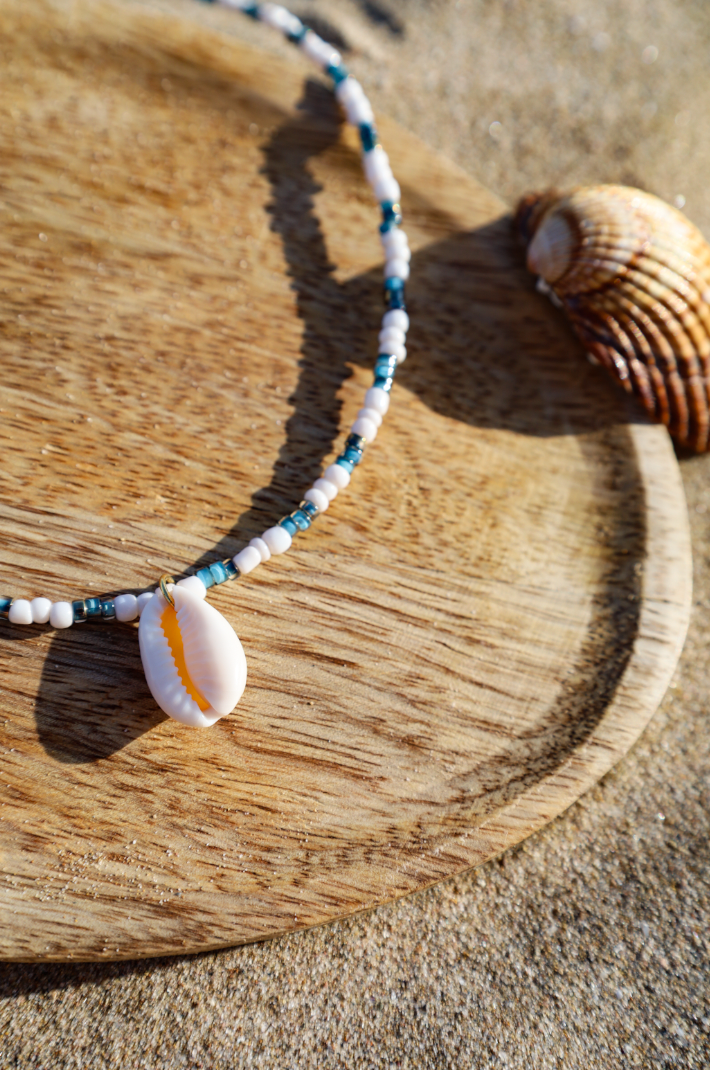 Collier composé de perles de petites rocailles couleur bleue avec pendentif cauri