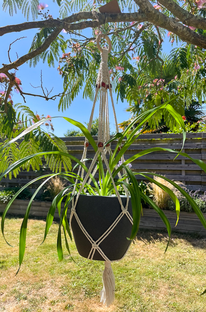 Suspension en macramé pour porter un pot avec une plante, tressé avec des perles en bois.