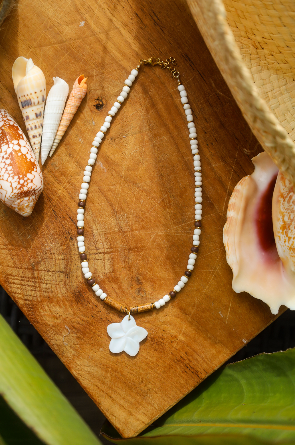 Collier en perles de rocailles blanches et une pointe de marron avec un pendentif en fleur de nacre.