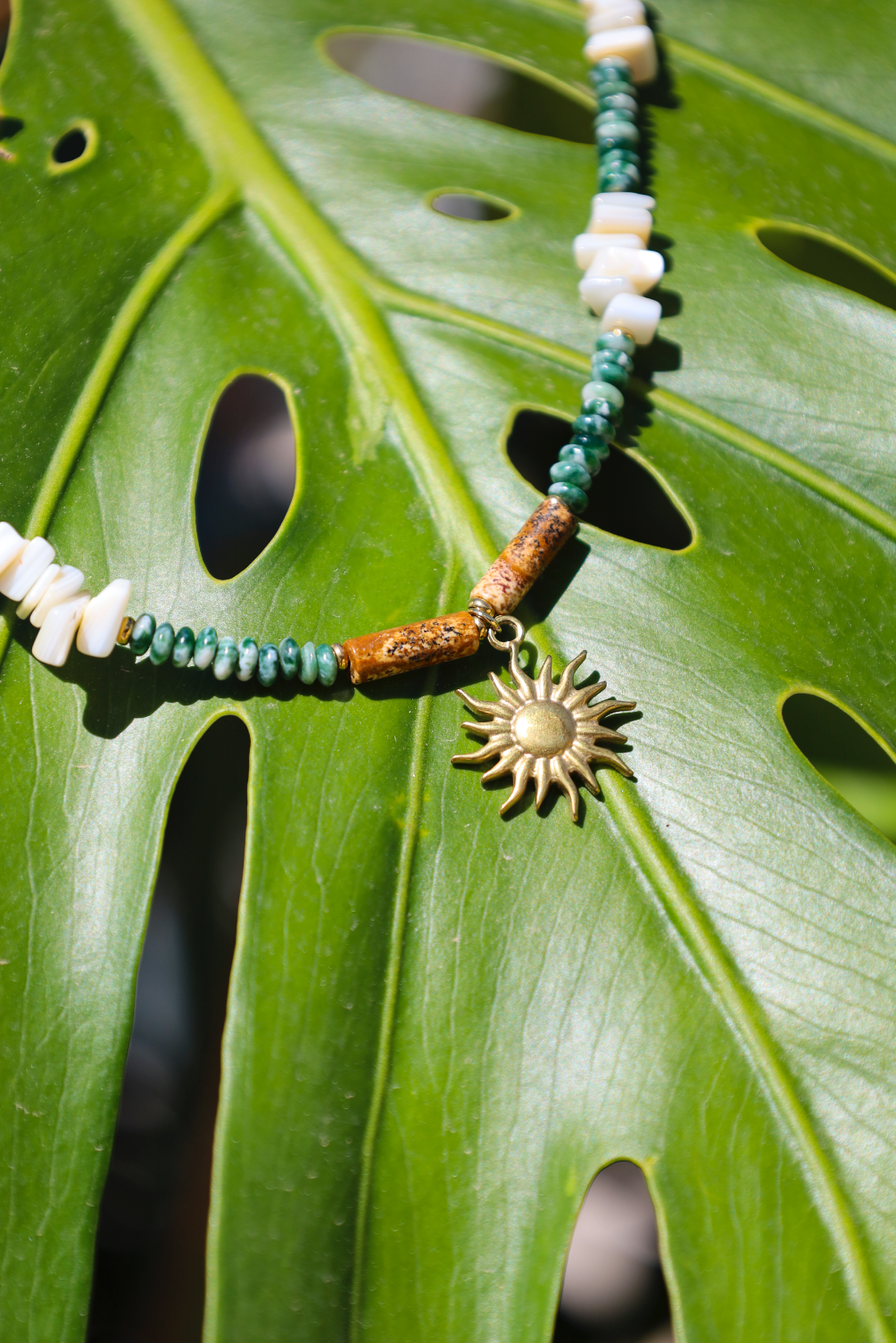 Collier en perles de jades vertes et en perles naturelles blanches avec pendentif soleil.