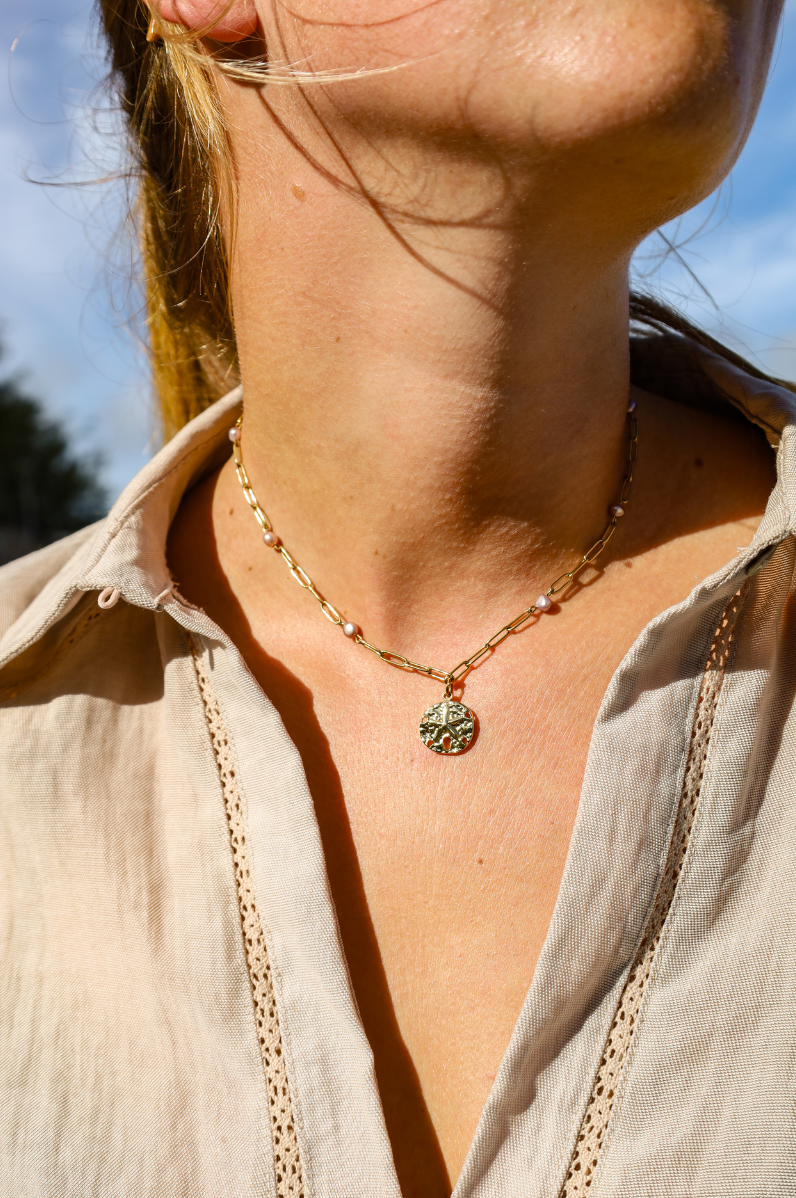 Collier en chaine dorée et perles de cultures violetes au pendentif dollar des sables