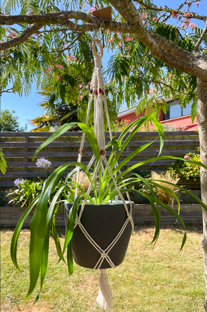 Suspension en macramé pour porter un pot avec une plante, tressé avec des perles en bois.